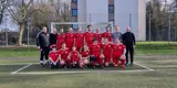 Das Team steht in zwei Reihen vor einem Tor