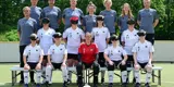 Teamfoto mit den Spielerinnen in weißen Trikots, Staff dahinter in grauen Shirts